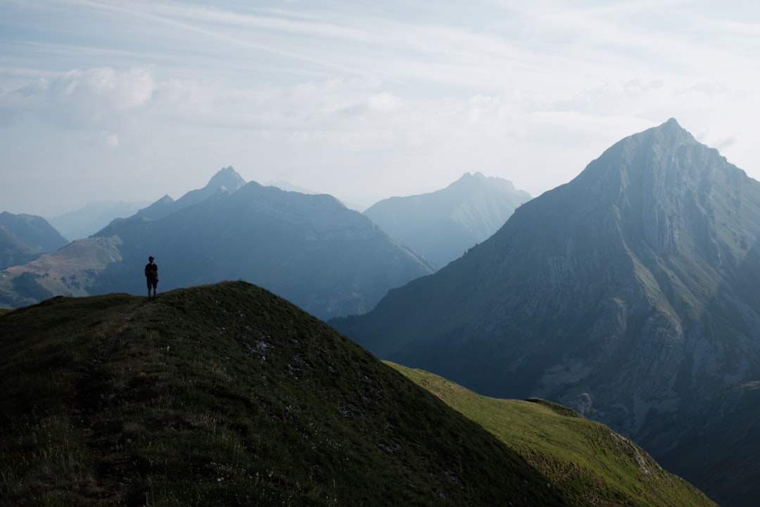A person dressed in business casual attire stands on a peak looking out over a vast mountain range, symbolizing the new opportunities and perspective gained by moving beyond the corporate structure.
