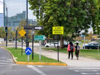 Professionally dressed person stands at a fork in a path, contemplating which direction to take, symbolizing the choice be...