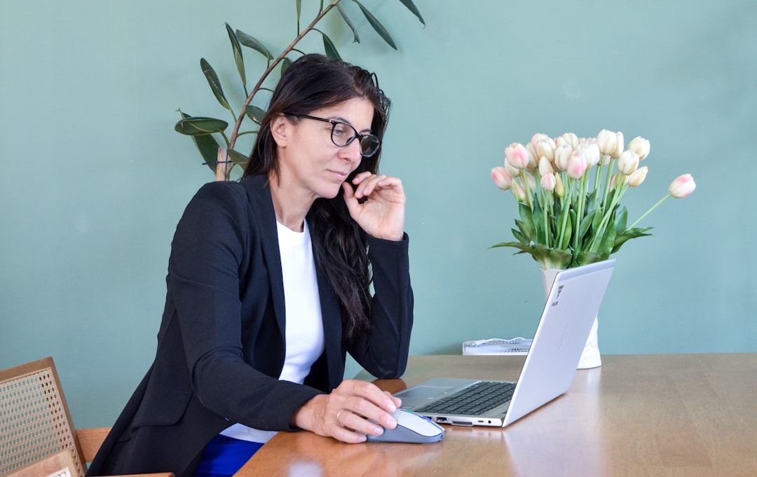 A homeowner sits at a sunlit wooden desk with a calculator, pen, and documents, carefully planning the costs associated with selling their property.