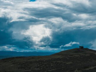 Well-lit, sturdy modern home stands securely under a dark and dramatic stormy sky, representing a safe shelter and financi...