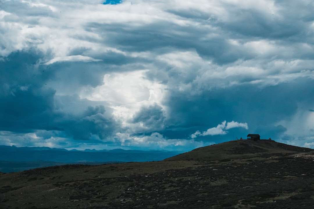 Well-lit, sturdy modern home stands securely under a dark and dramatic stormy sky, representing a safe shelter and financi...