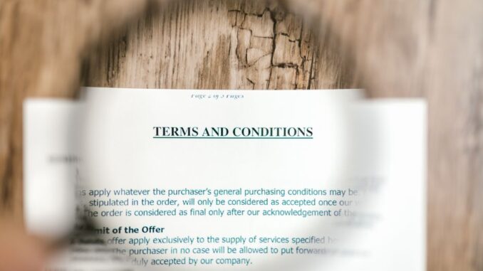 Close-up of a person in professional attire using a magnifying glass to carefully inspect the details of a real estate doc...