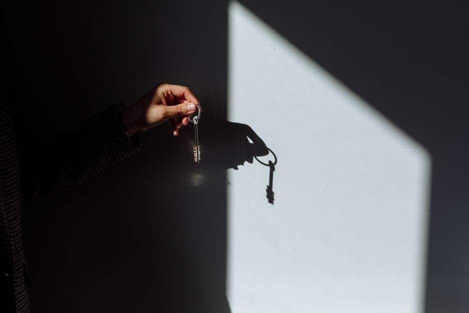 A person's hand carefully selecting a single, distinct house key from a collection of different keys, symbolizing making a thoughtful choice.