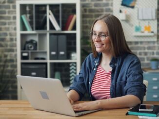 Professional short-term rental owner sitting at a bright, modern desk, using a laptop and notepad to organize their busine...