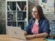 Professional short-term rental owner sitting at a bright, modern desk, using a laptop and notepad to organize their busine...