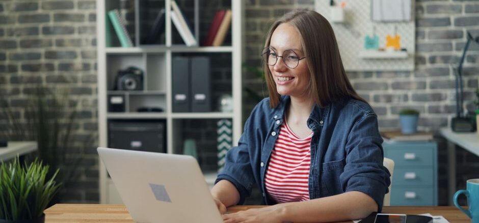 Professional short-term rental owner sitting at a bright, modern desk, using a laptop and notepad to organize their busine...