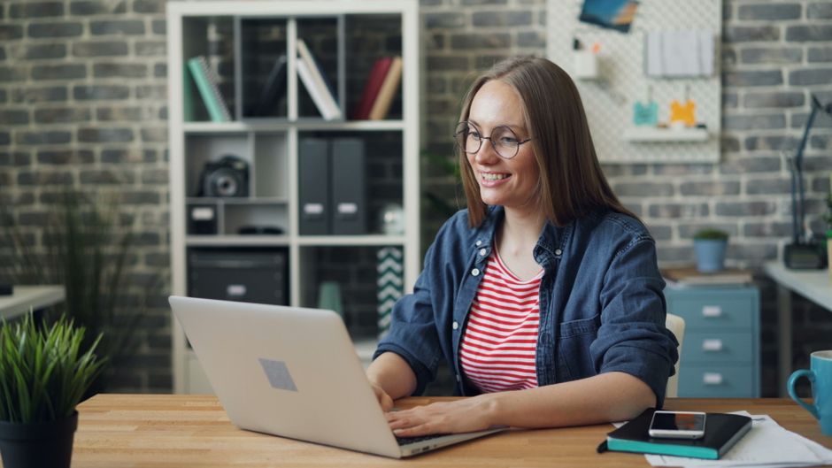 Professional short-term rental owner sitting at a bright, modern desk, using a laptop and notepad to organize their busine...